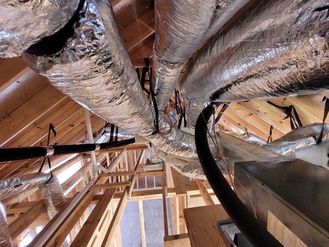 A bunch of ducts are hanging from the ceiling of a building