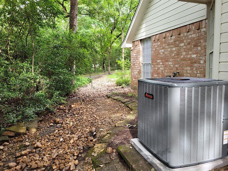 An air conditioner is sitting on the side of a brick house.