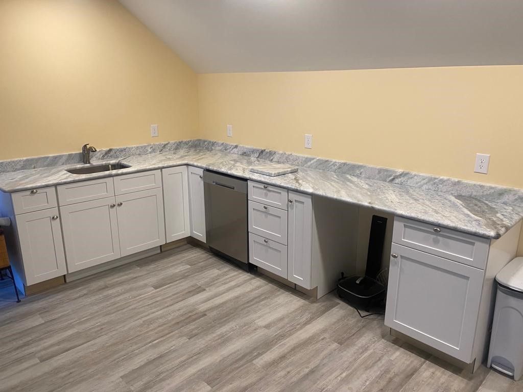 A kitchen with white cabinets , granite counter tops , and stainless steel appliances.
