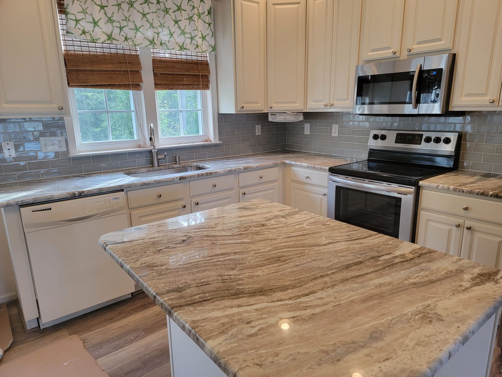 A kitchen with granite counter tops , stainless steel appliances , and white cabinets.