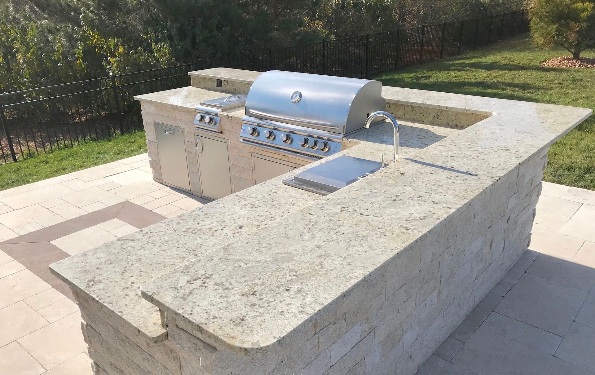 A large outdoor kitchen with a grill and a sink