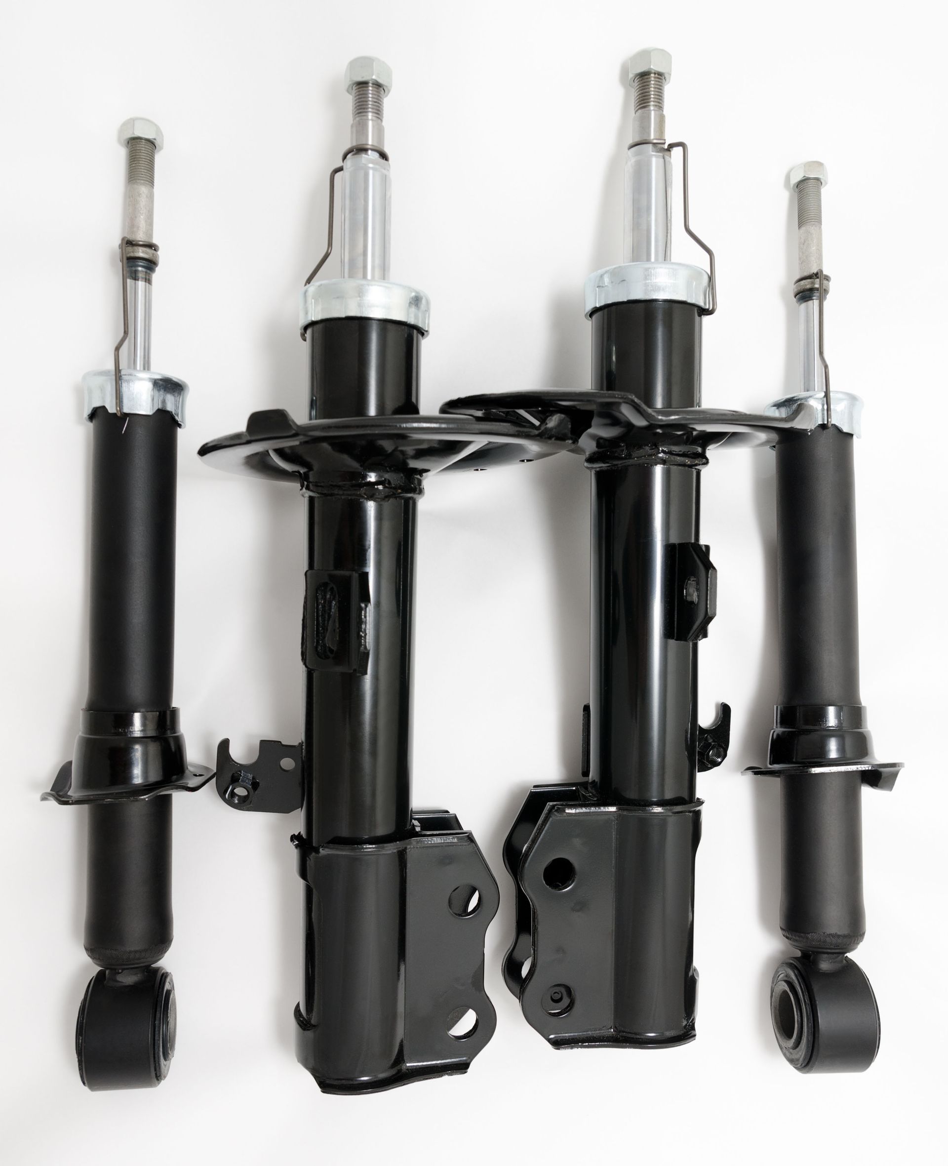 Four black car shock absorbers arranged on a white background.