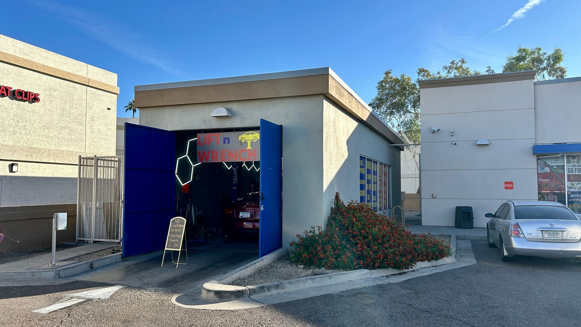 Lift n Wrench auto shop exterior with neon lights, car lift, and sign, featuring a yellow car graphic.