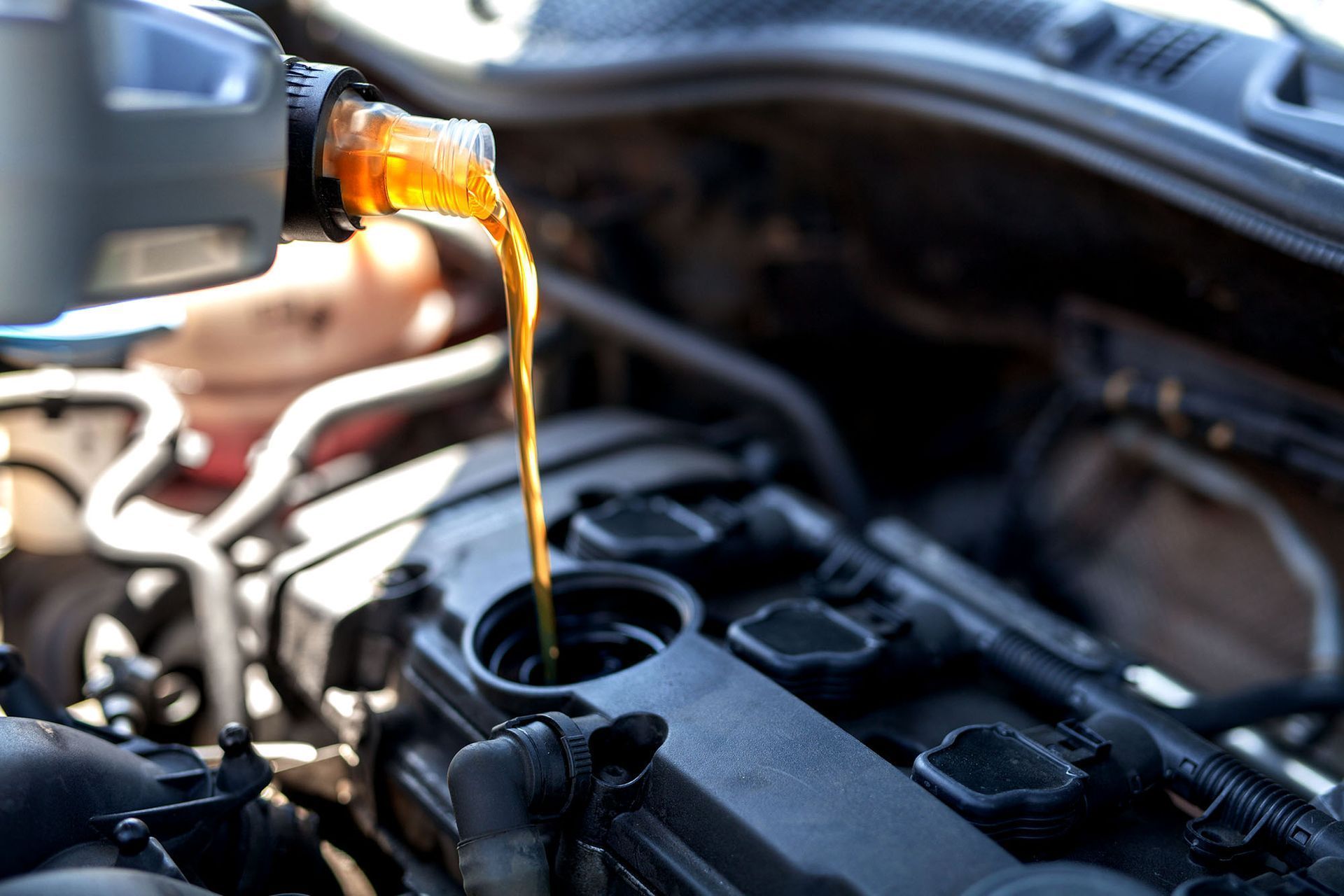 Oil being poured into a car engine, likely during an oil change.