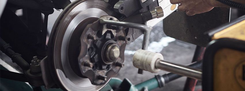 Person pouring fresh yellow motor oil into a car break.