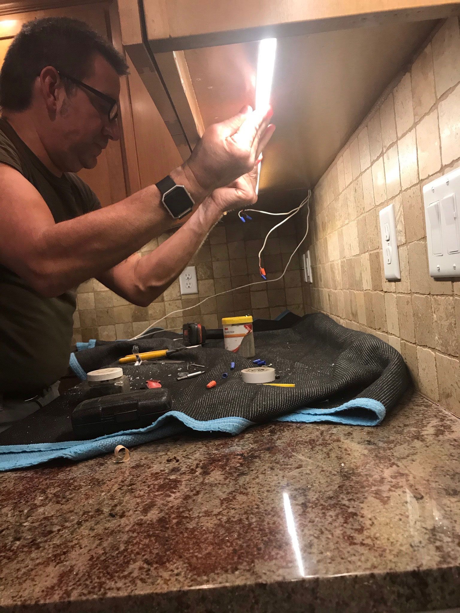 Person in a kitchen using a lighter near a stove under the range hood, with a towel on the counter.