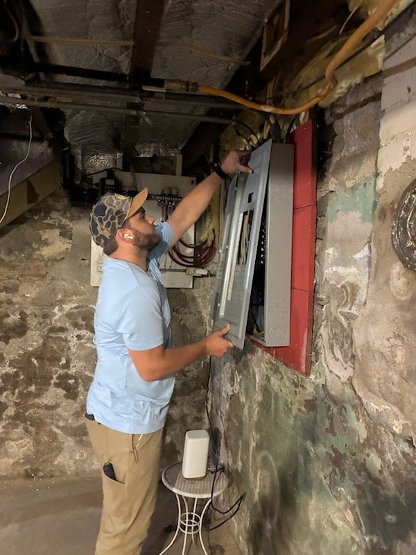 Person installing a red-framed window in a partially finished basement with exposed walls and ceiling