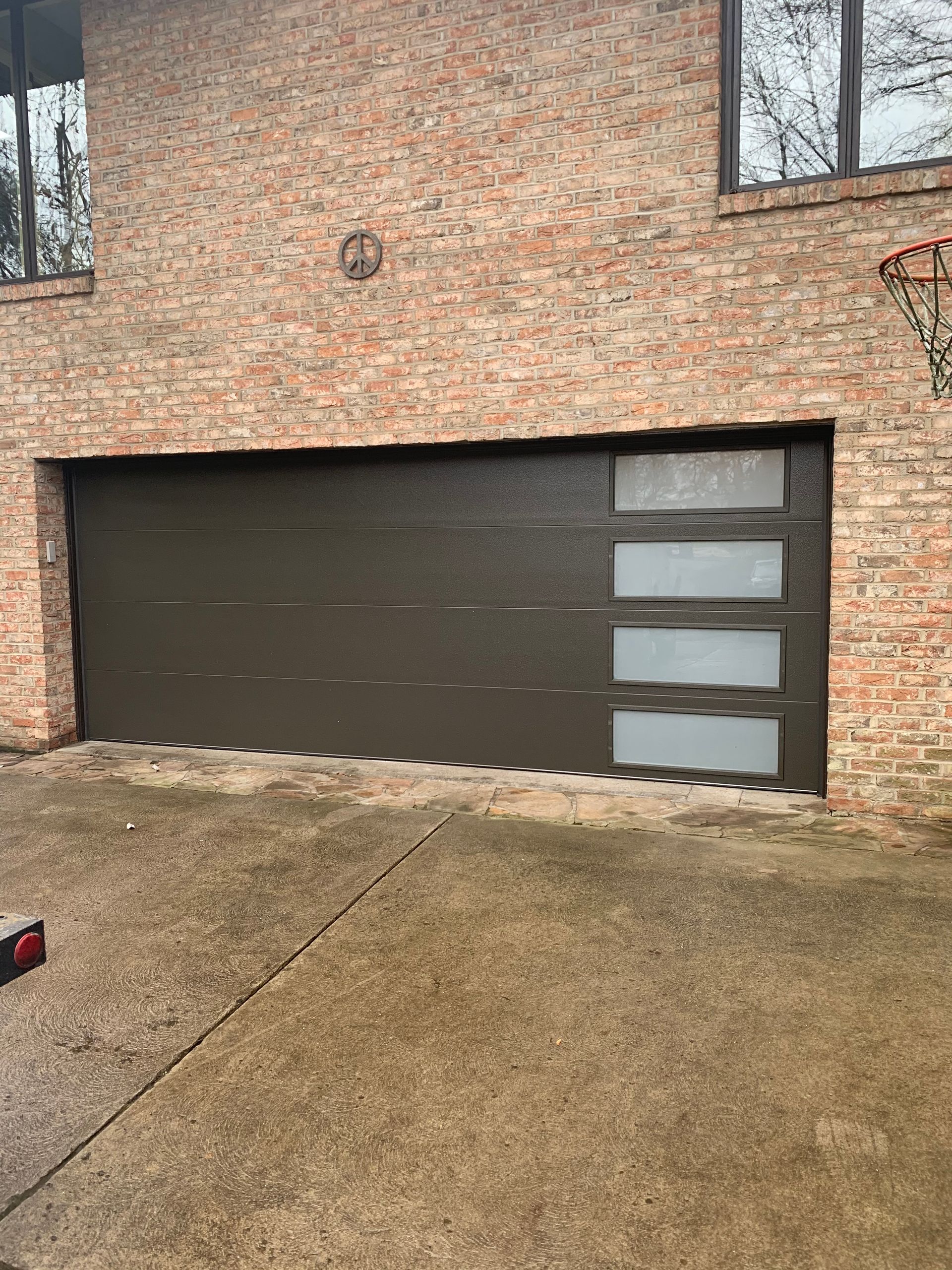 Brown garage door with frosted glass panels on a brick building.