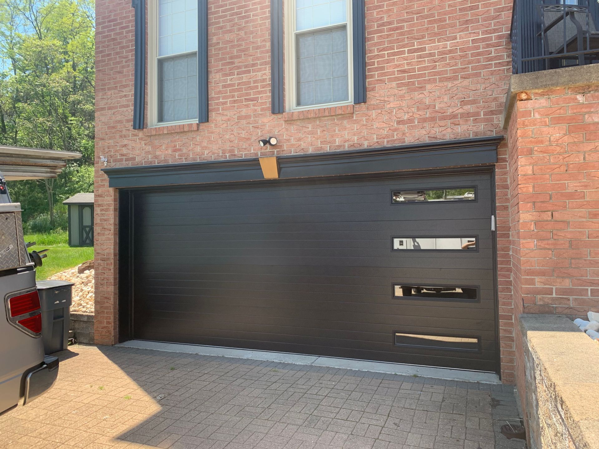 Black garage door with rectangular windows, brick building exterior.