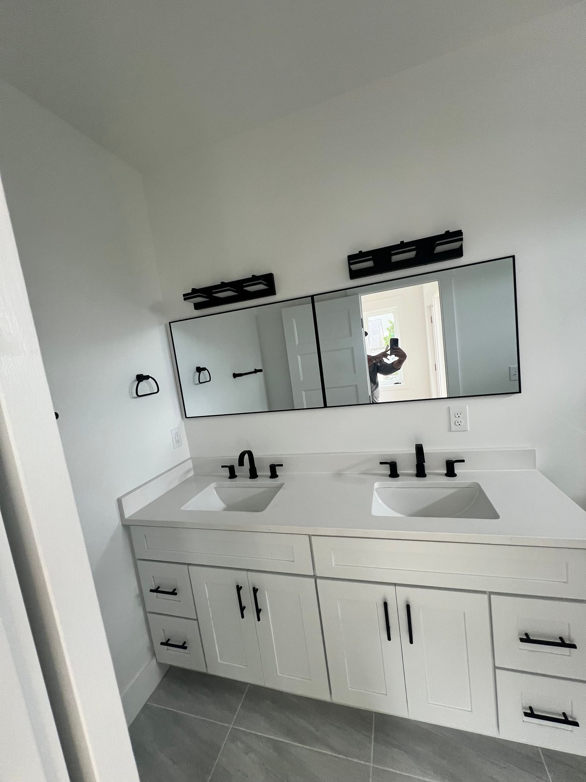 Modern white bathroom vanity with two sinks, black fixtures, and rectangular mirrors.