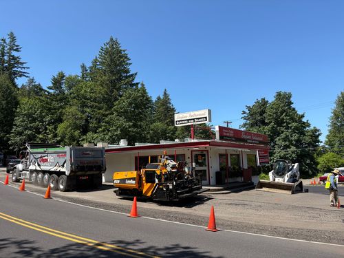 Roadside food stand with parked trucks, orange cones, and a utility worker under a clear blue sky
