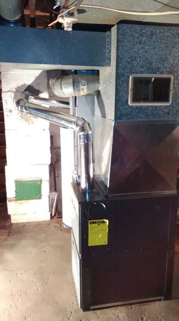 Furnace system in a basement setting with exhaust and ductwork. Black, silver, and gray colors.