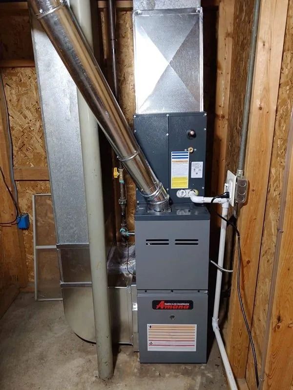 A natural gas furnace, in a wooden-walled utility room, with attached ductwork and vent pipe.