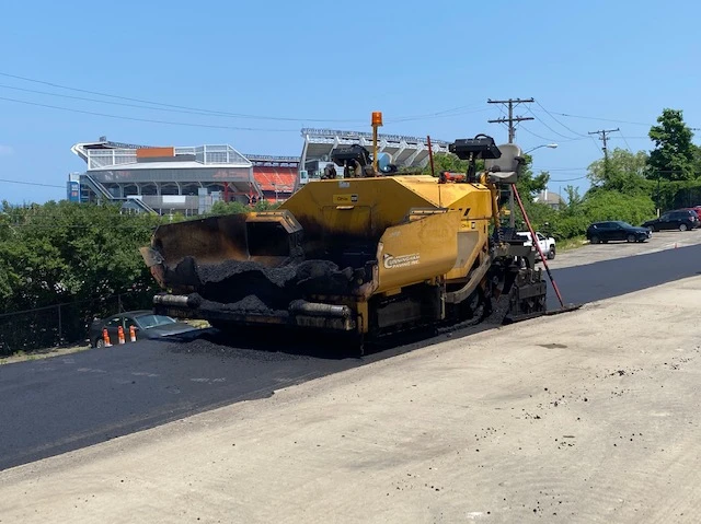 a yellow asphalt paving machine is sitting on the side of a road