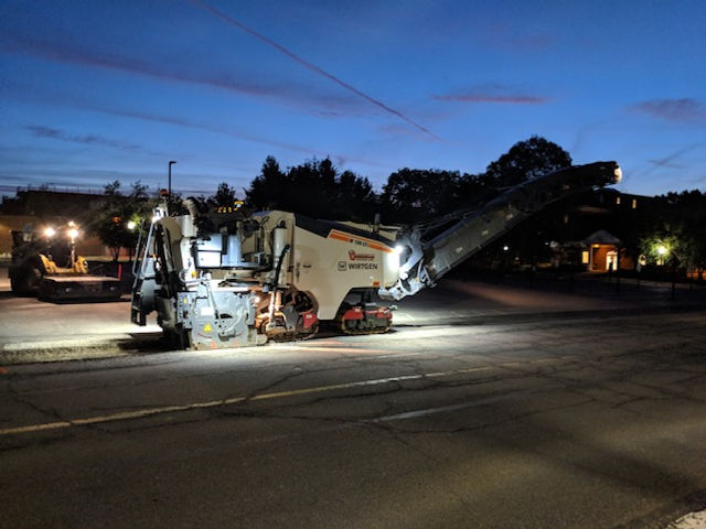 a large machine is sitting on the side of the road at night