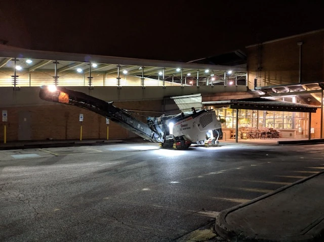 a machine is working on the road at night in front of a building 