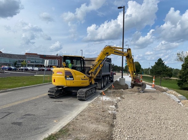 a yellow excavator is parked on the side of the road next to a dump truck 