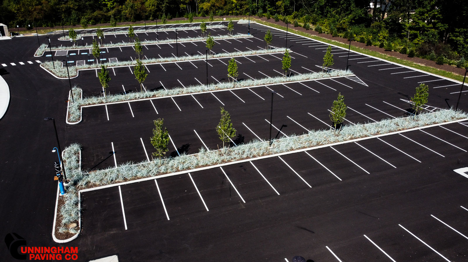 an aerial view of a parking lot with trees in the middle