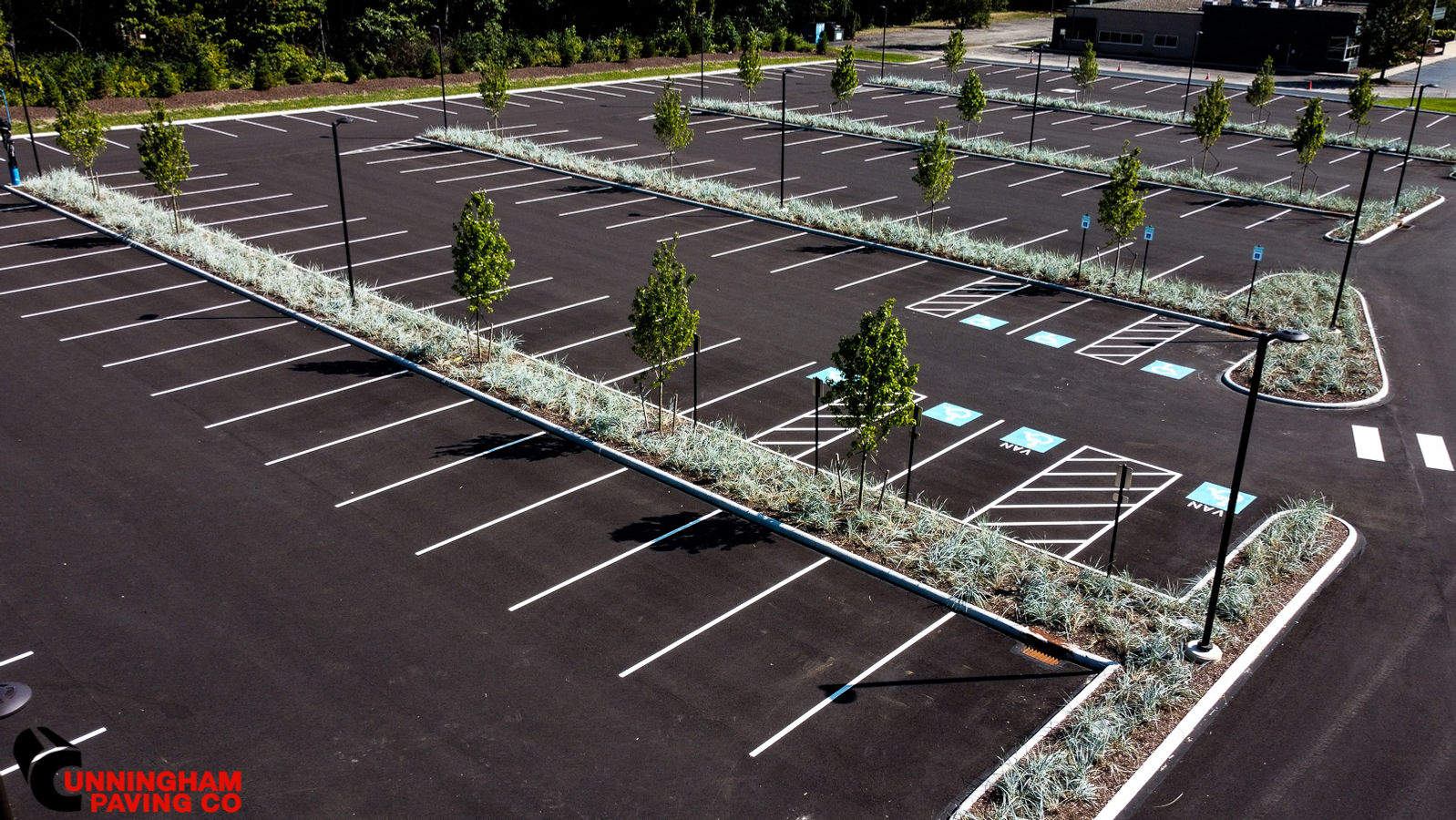 an aerial view of a parking lot with trees in the middle