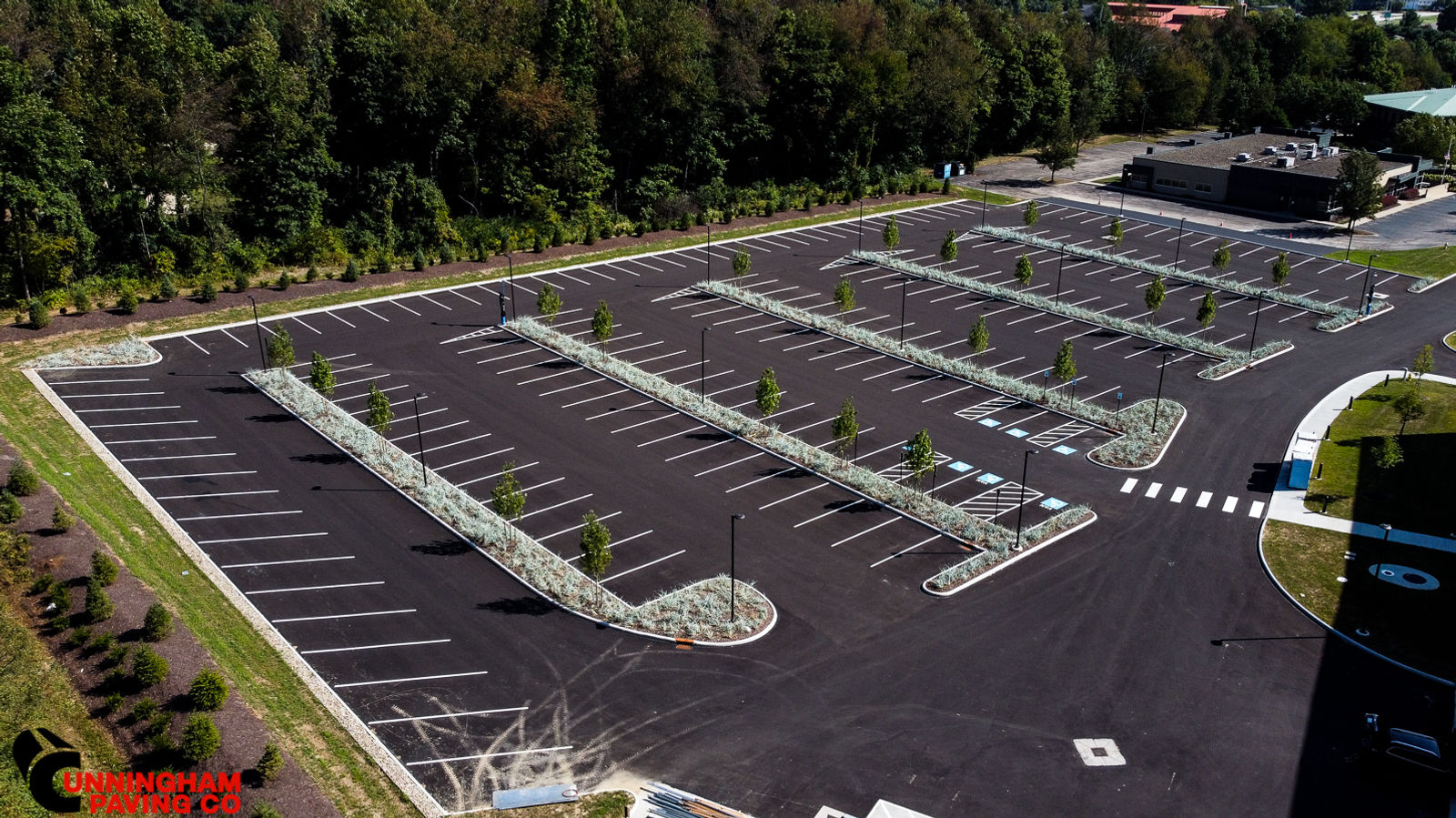 an aerial view of a parking lot with trees in the background