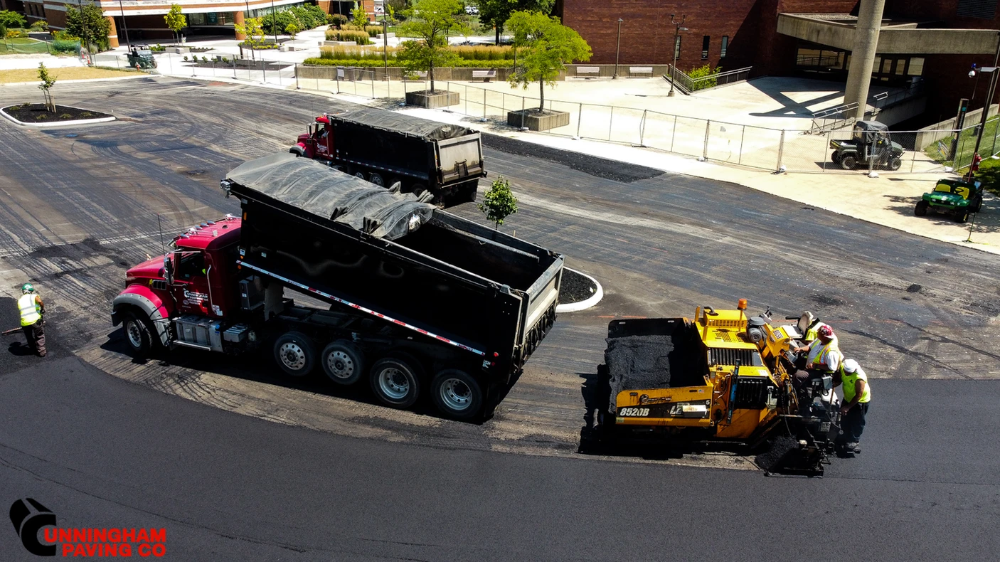a dump truck is being loaded with asphalt in a parking lot