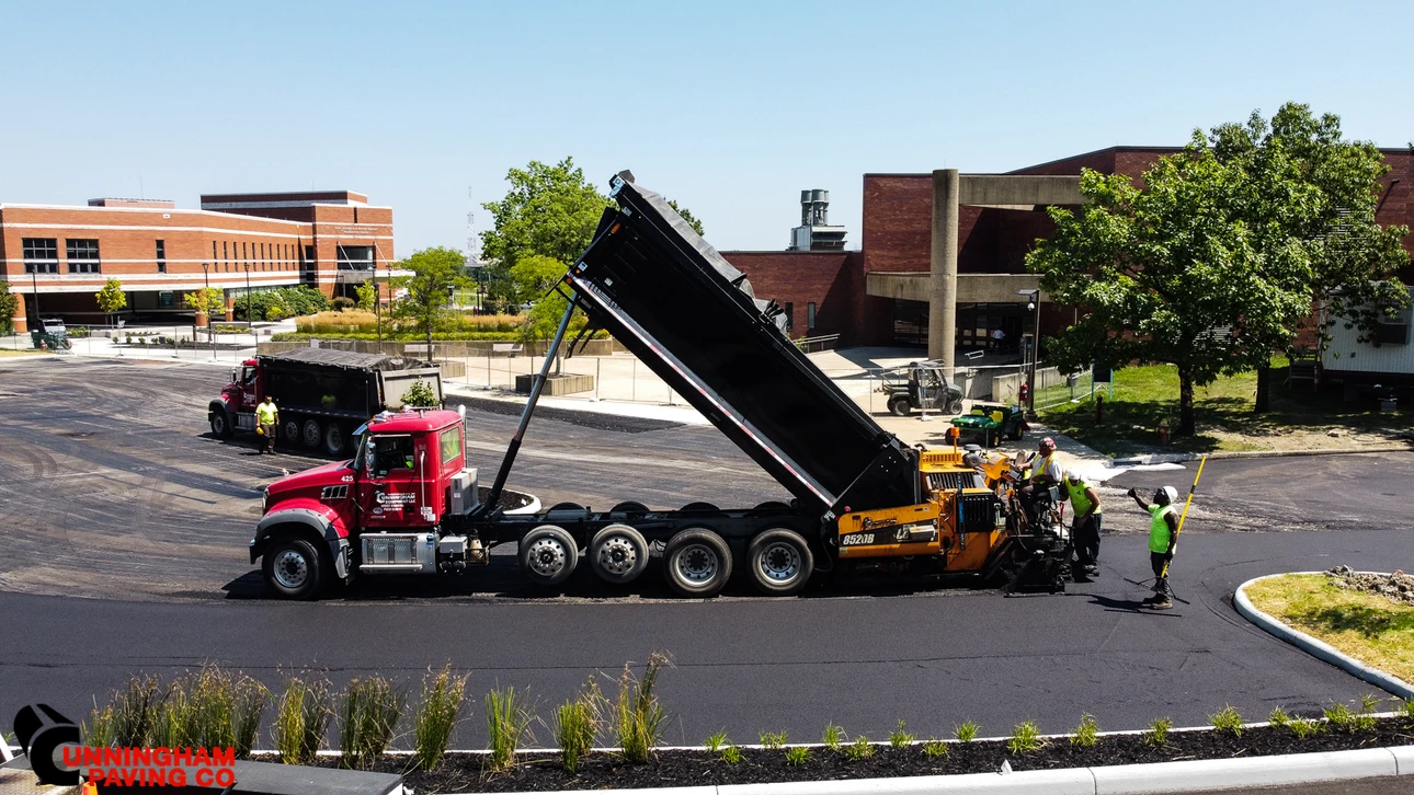 a dump truck is being loaded with asphalt in a parking lot