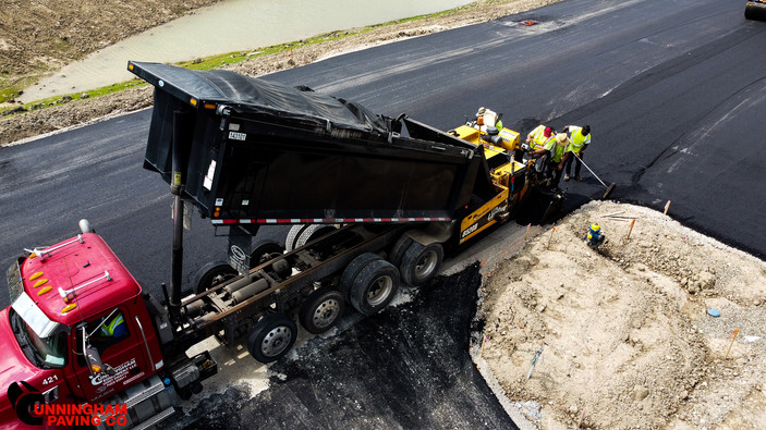 a dump truck is being loaded with asphalt on a road