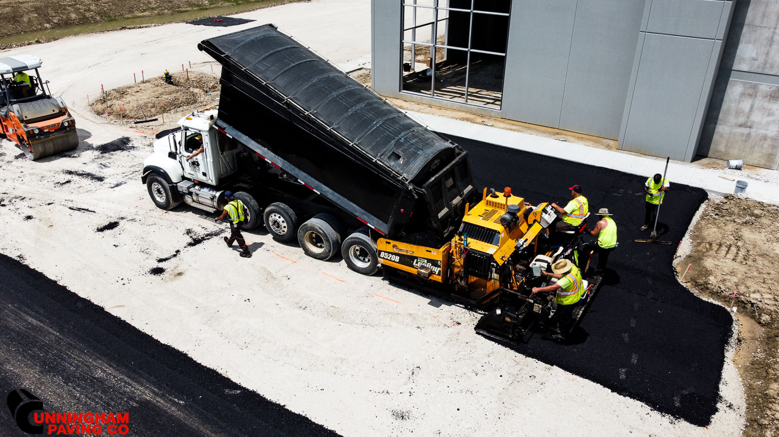 an aerial view of a dump truck being loaded with asphalt