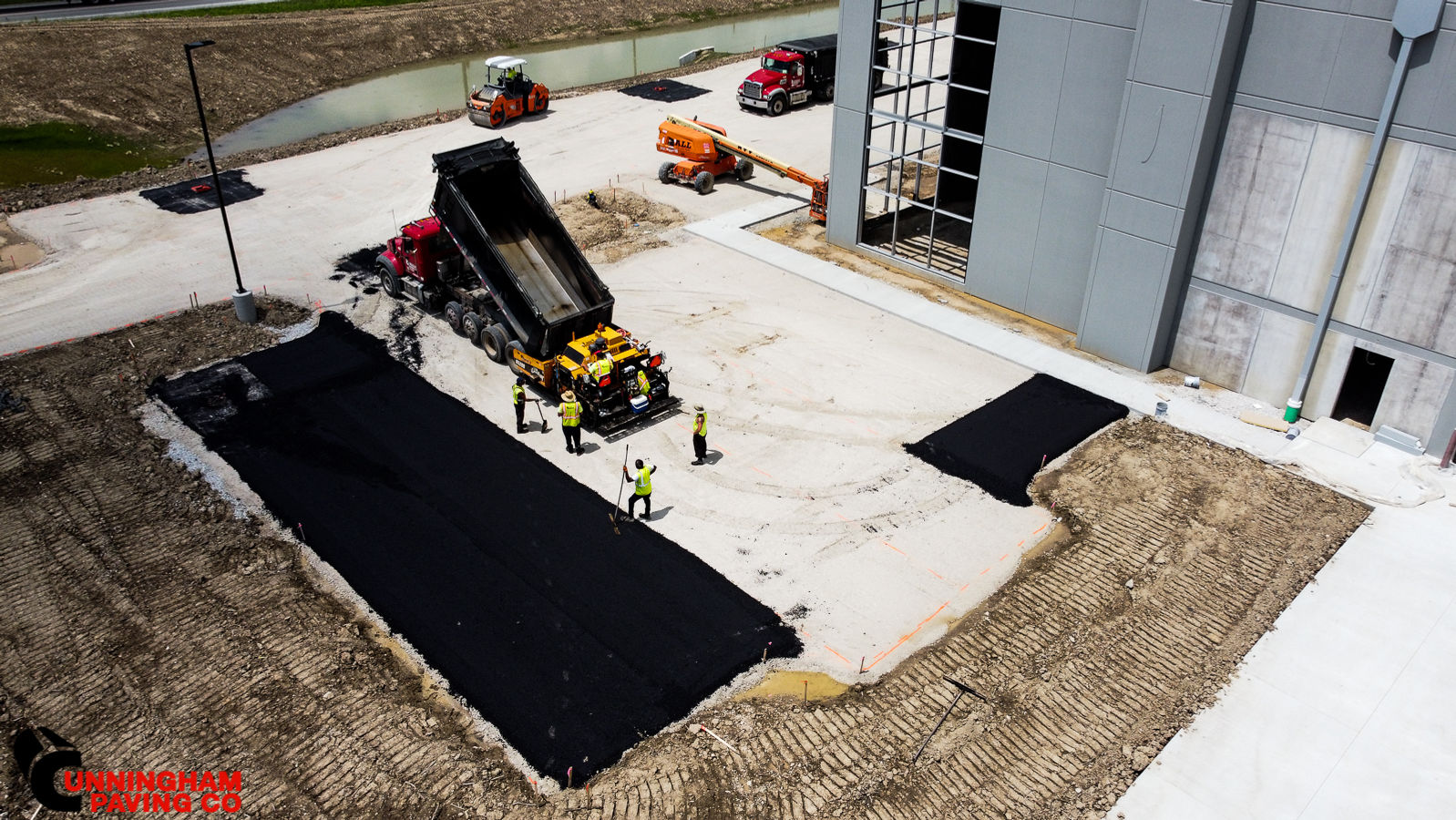 an aerial view of a construction site with a dump truck being loaded with asphalt