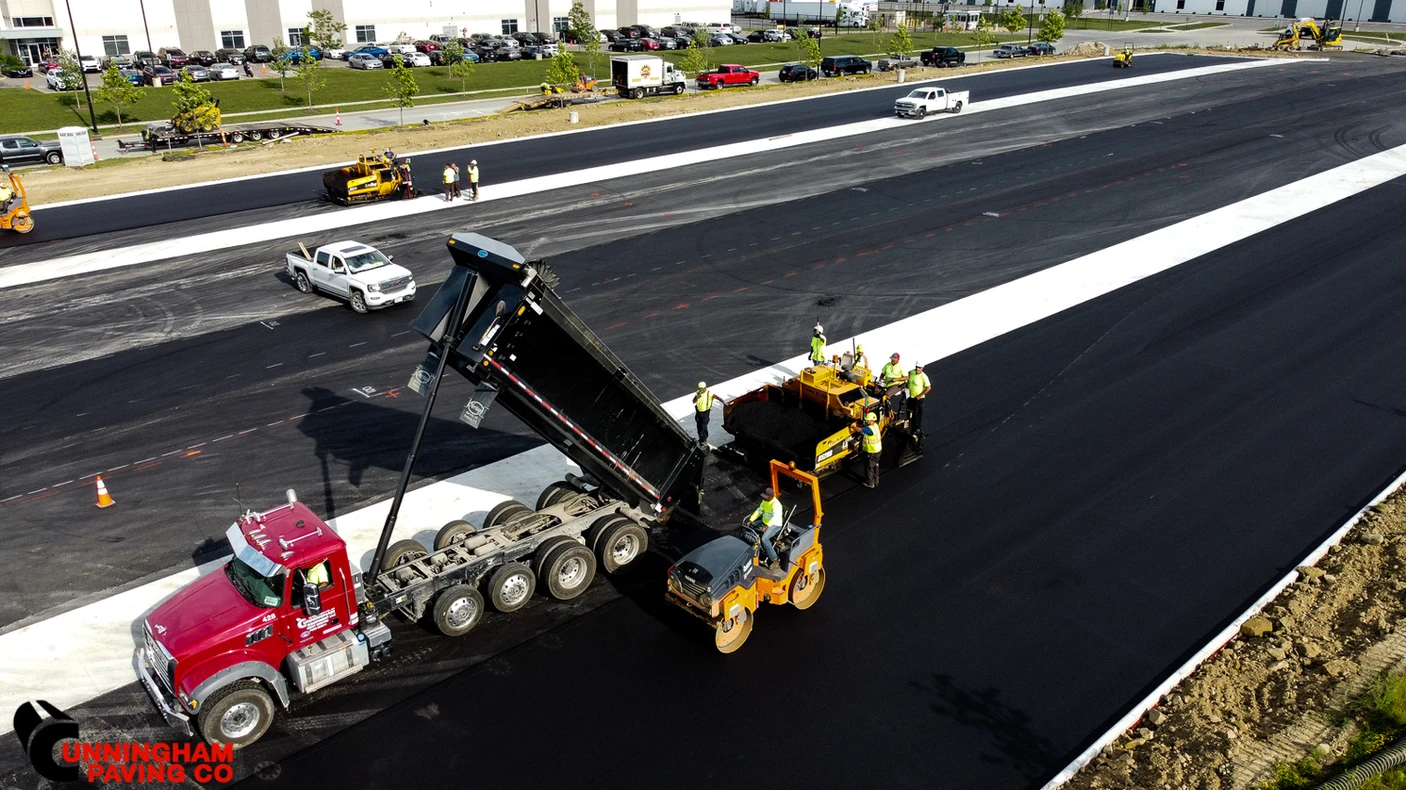 an aerial view of a truck dumping asphalt on a highway