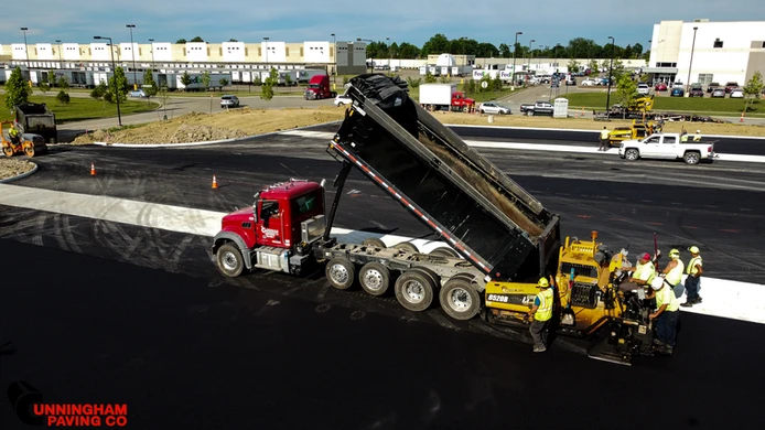 a dump truck is being loaded with asphalt on a construction site