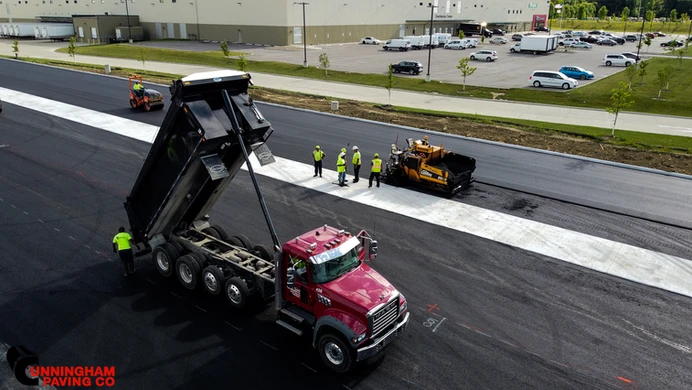 an aerial view of a dump truck being loaded with asphalt