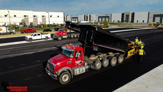 a red dump truck is driving down a road next to a building