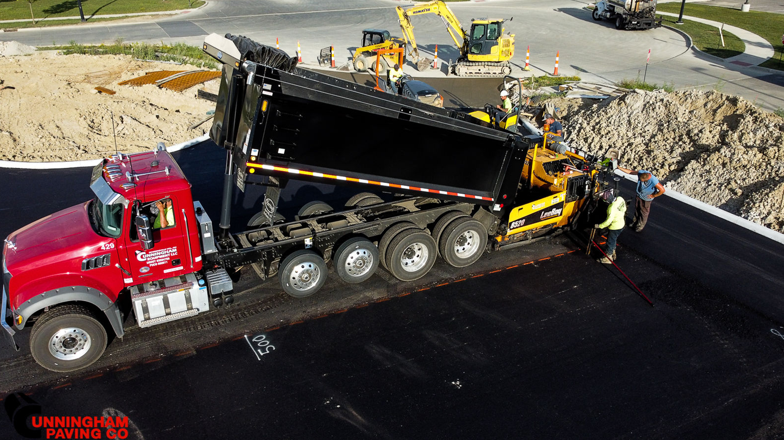 an aerial view of a dump truck being loaded with asphalt at a construction site