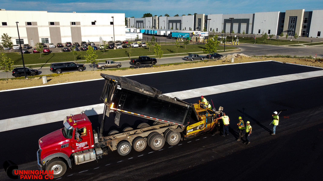 an aerial view of a dump truck being loaded with asphalt
