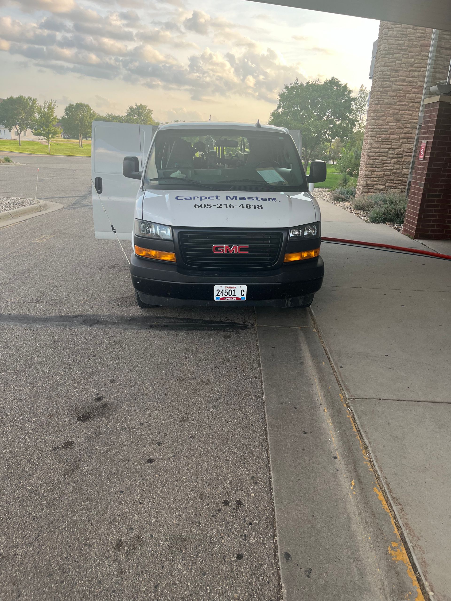 A white van is parked on the side of the road in front of a building.