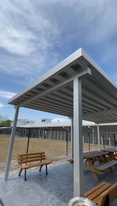 A pergola with a picnic table and benches underneath it