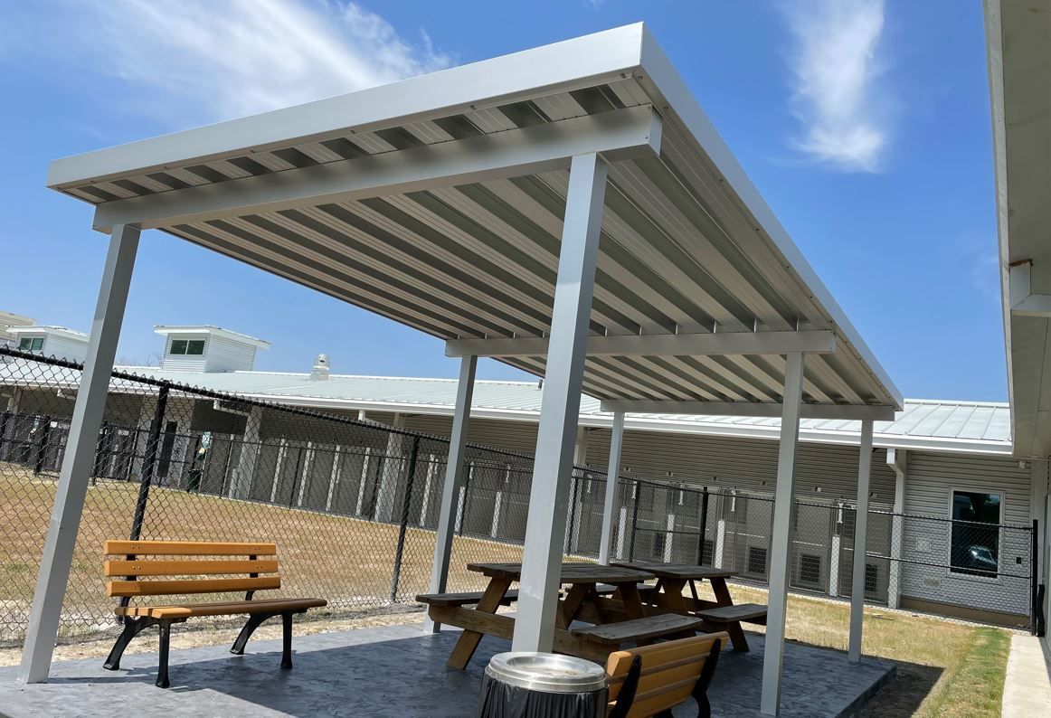 A covered area with tables and benches under a canopy