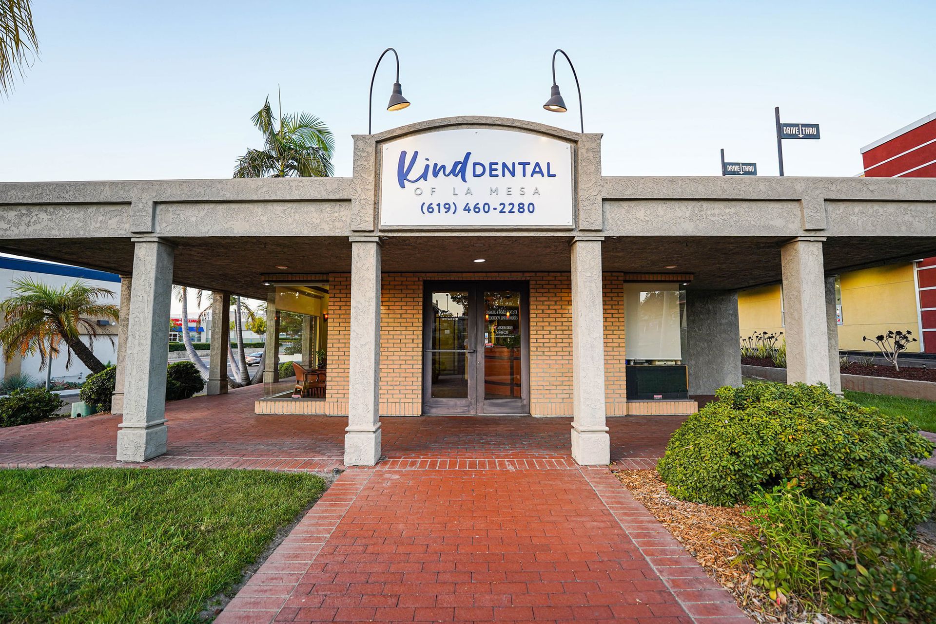 Kind Dental building with brick path, columns, and arched entrance.