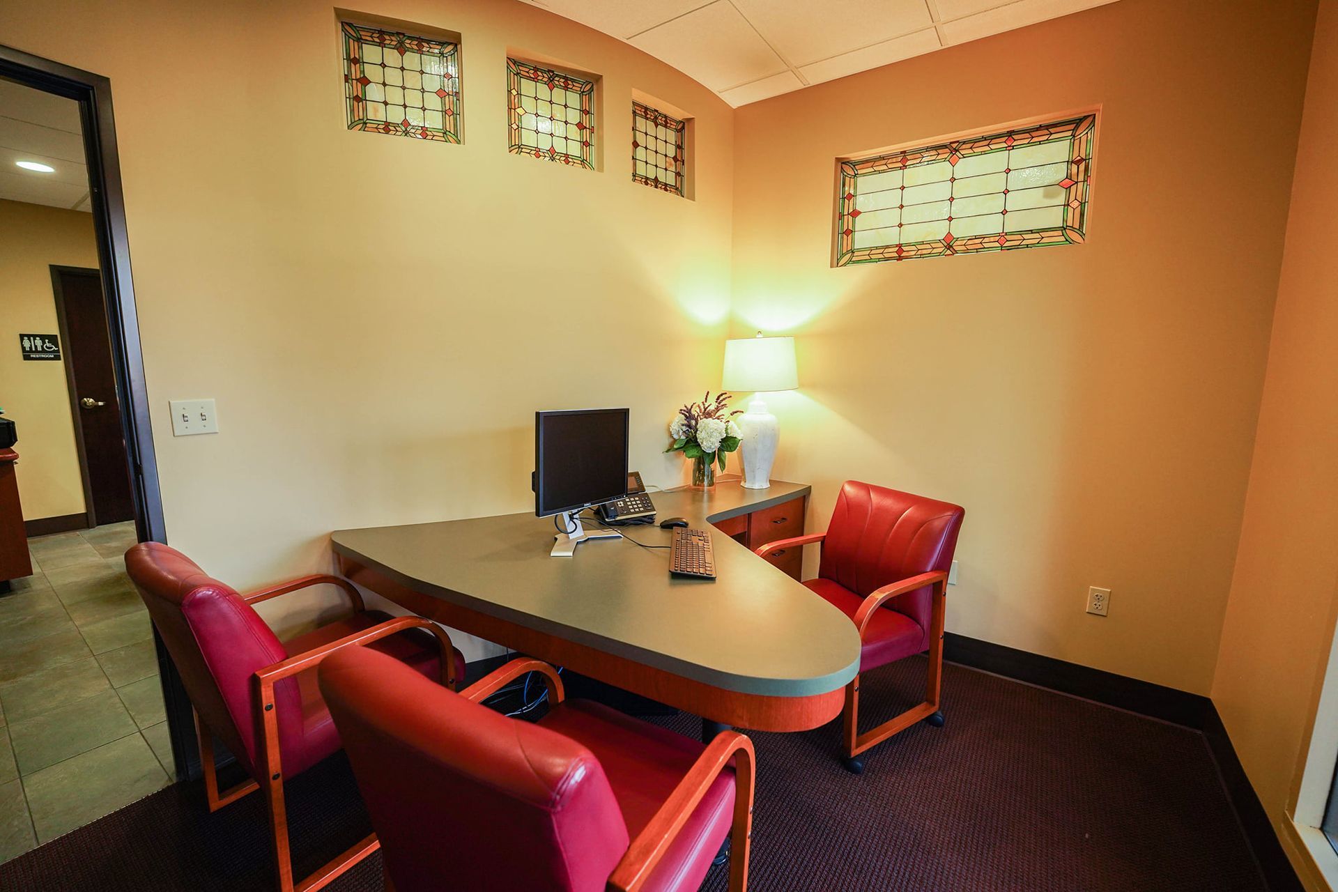 Office room with a desk and red chairs.