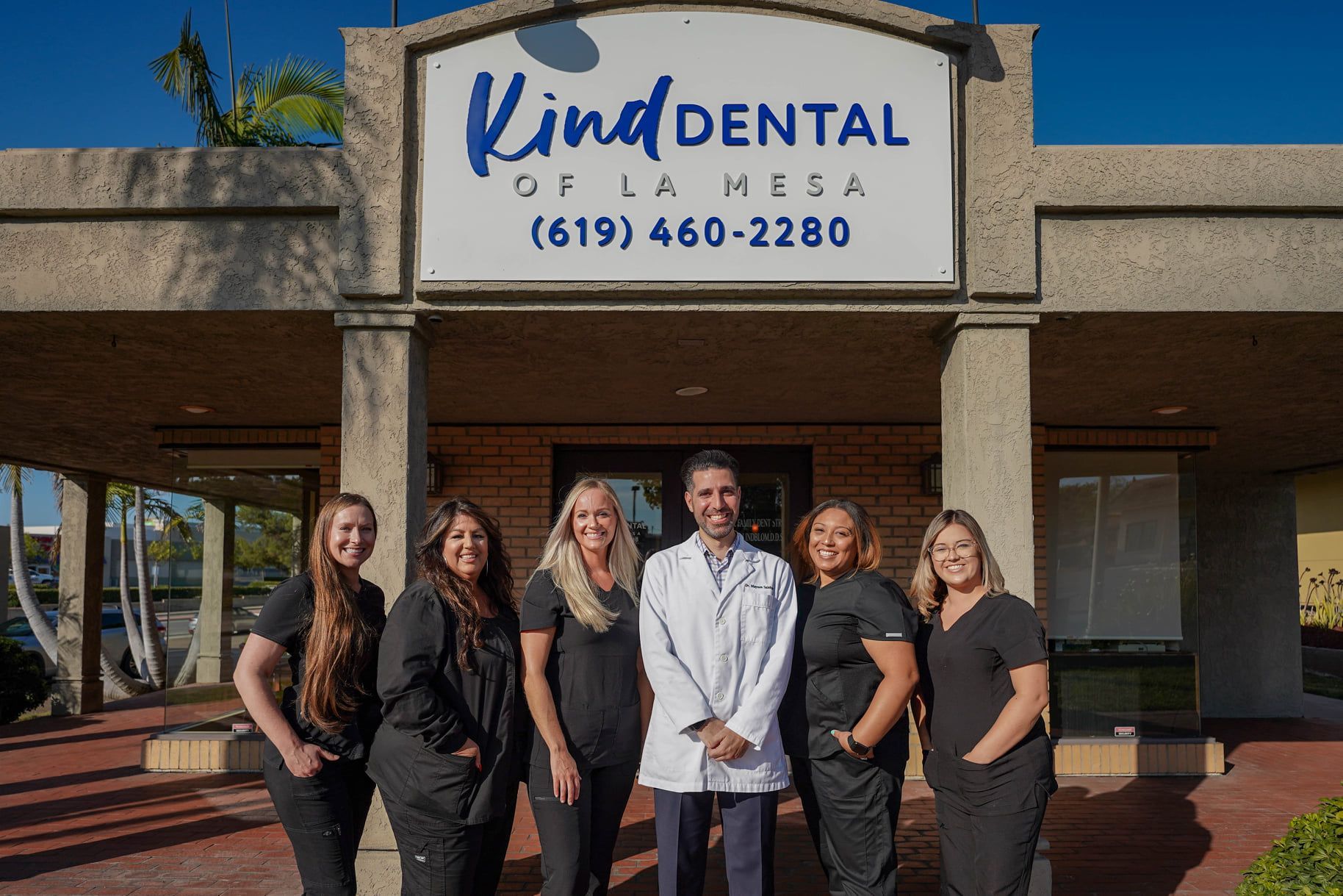 Staff of Kind Dental of La Mesa smiling in front of their office.