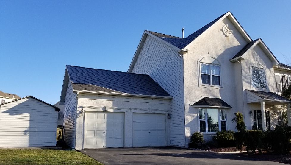 White two-story suburban house with a garage and blue roof under a clear sky