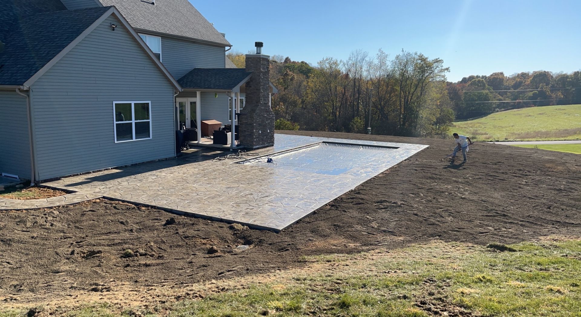 Concrete patio being built next to a two-story gray house.