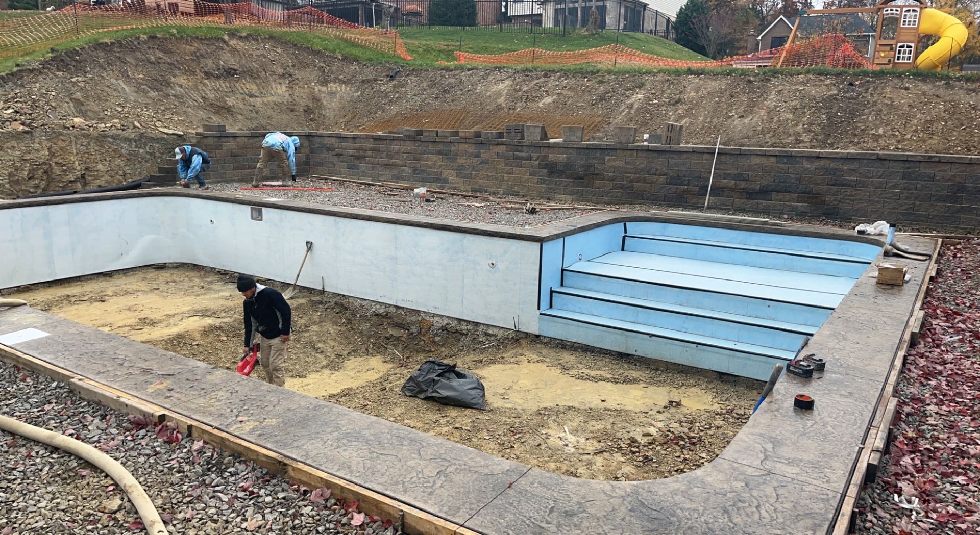 Pool under construction with workers. The pool's interior features steps and blue insulation.