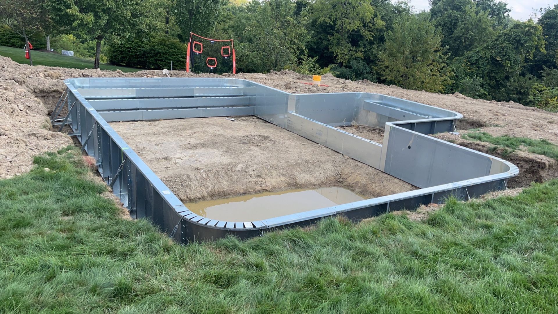 A rectangular pool framework under construction on a grassy hill.