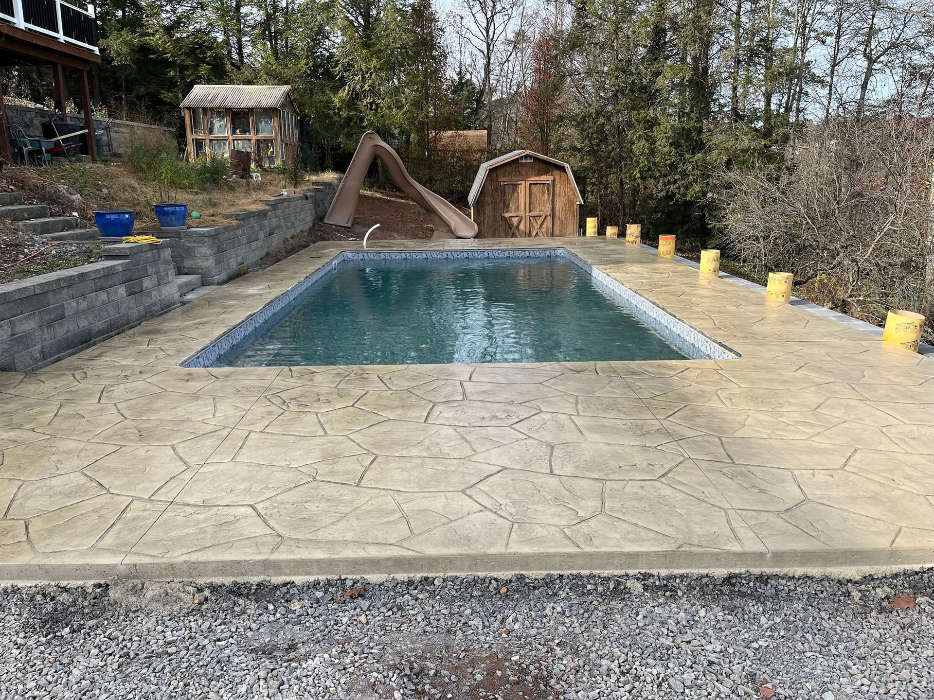 Rectangular pool with stamped concrete patio in a backyard setting, surrounded by landscaping.