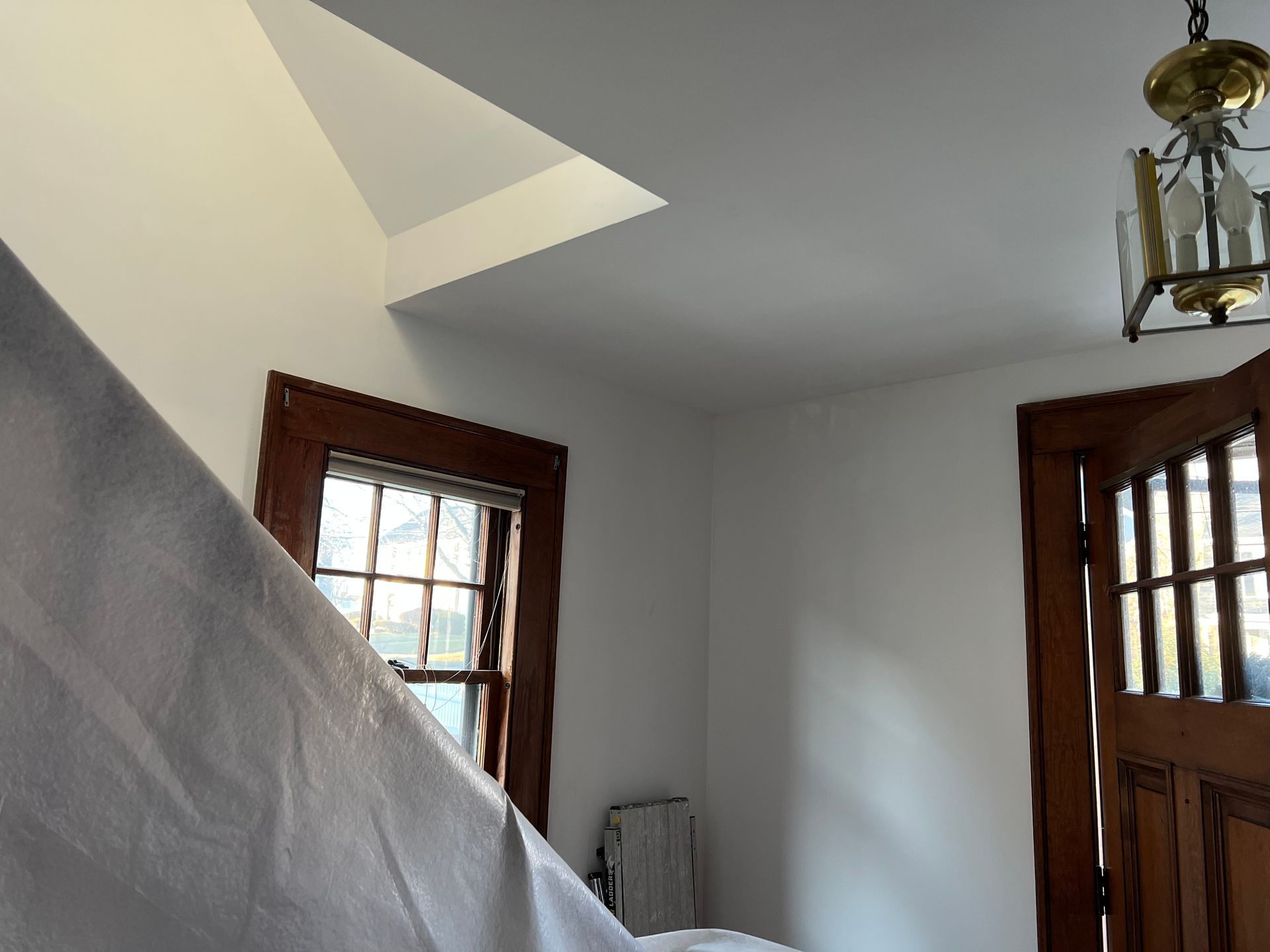 Bright stairwell with gray walls, wood-trimmed windows, and a hanging lantern light