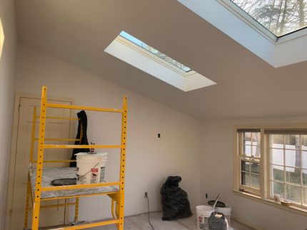 Room under renovation with yellow scaffold, skylight windows, and building materials on the floor