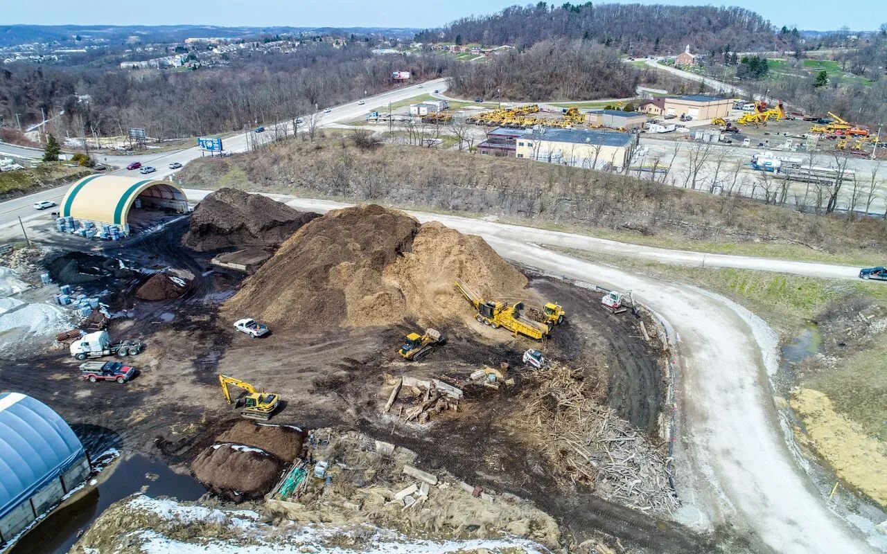 Aerial view of a construction site with large dirt piles, excavators, and winding dirt roads.