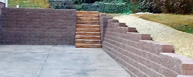 Outdoor brick retaining wall with steps leading up to a paved patio area